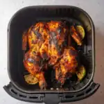 Crispy seasoned chicken cooked in an air fryer with a smoky, spicy glaze, garnished with lime slices for added zest.